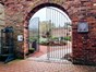 Metal gates in red brick wall leading to gardens 