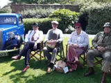 a group of peopple sat in deckchairs dressed in 1940s clothing