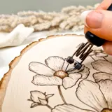 flower design being burned into end of log cut off