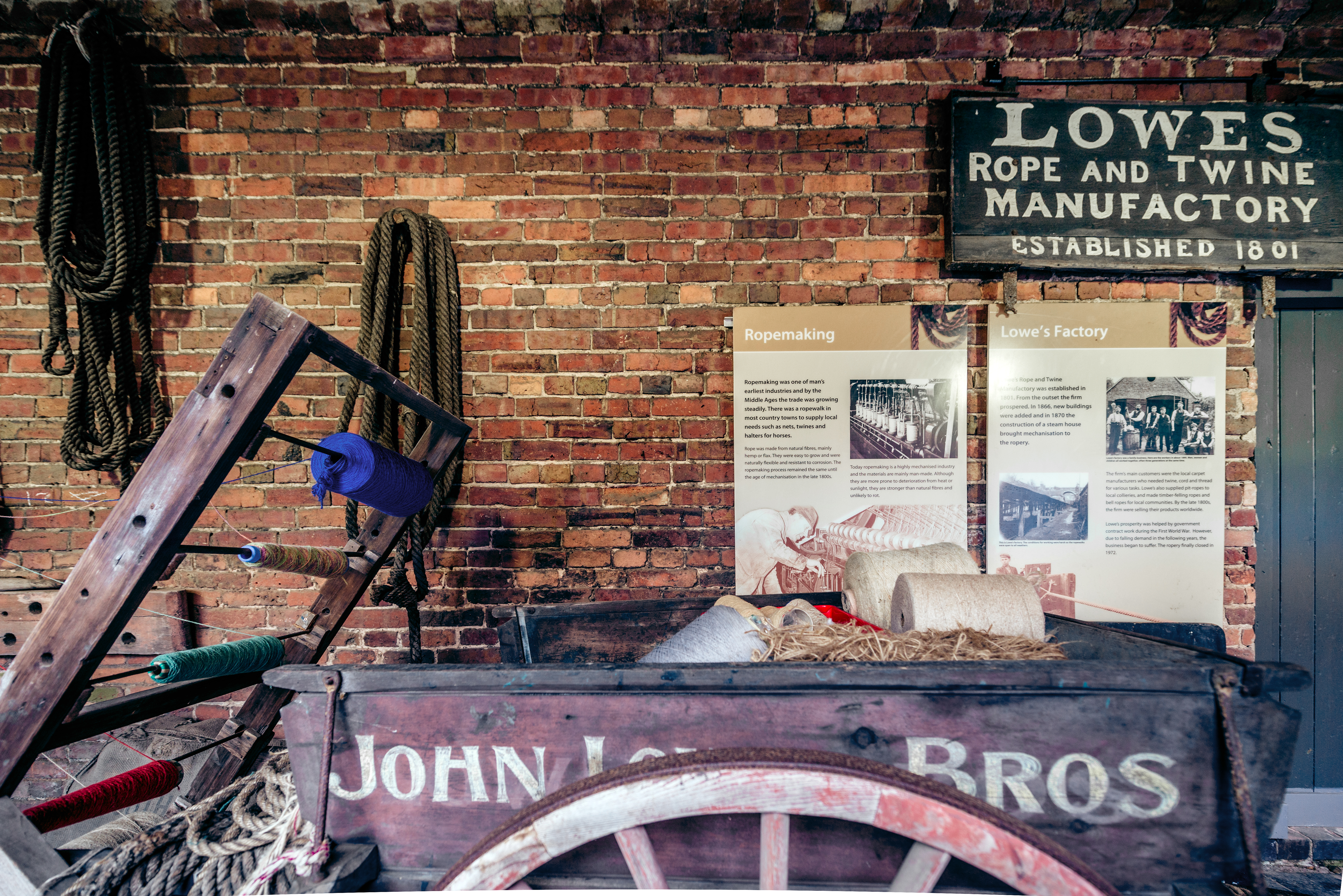 old fashioned cart in front of museum information boards on brick wall