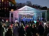 a group of people gathered together inoutdoor theatre singing Chrostmas carols at nighttime 