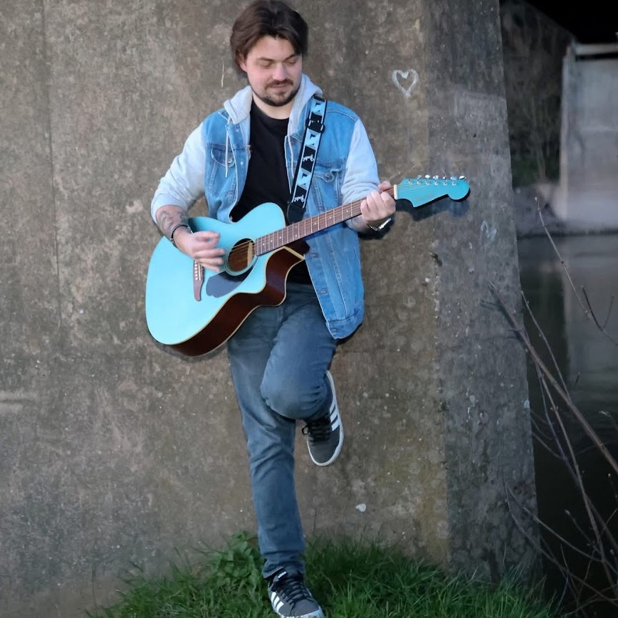 guitar player standing againsgt wall playing