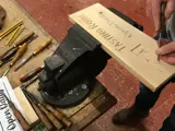 person carving their initials into wood using traditional methods