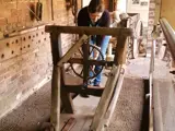 volunteer in modern clothing demonstrates historic rope making machinery