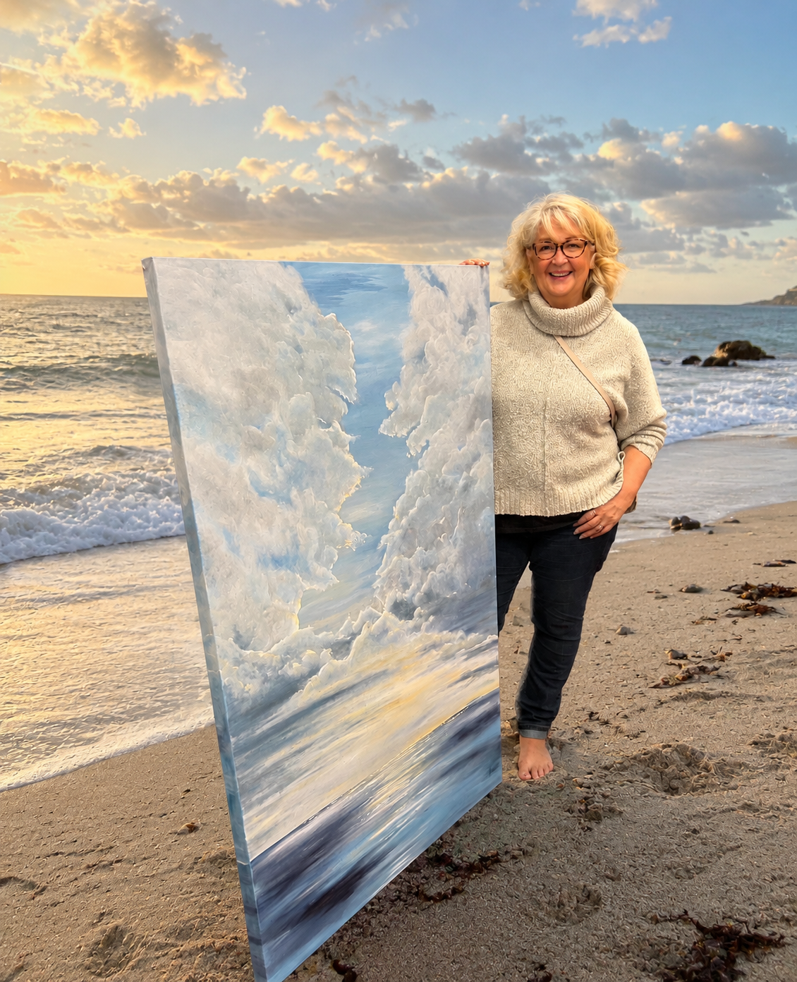 Artist should woith her artwork of the sea and sand with a sunset lit sky