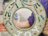 a circvular mosaic pieve in the theme of Chrsitmas with the words JOY written in mosaic tiles pieces