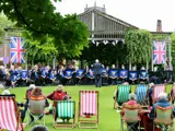 a brass band playing music with an audience seated in an outdoor theatre garden